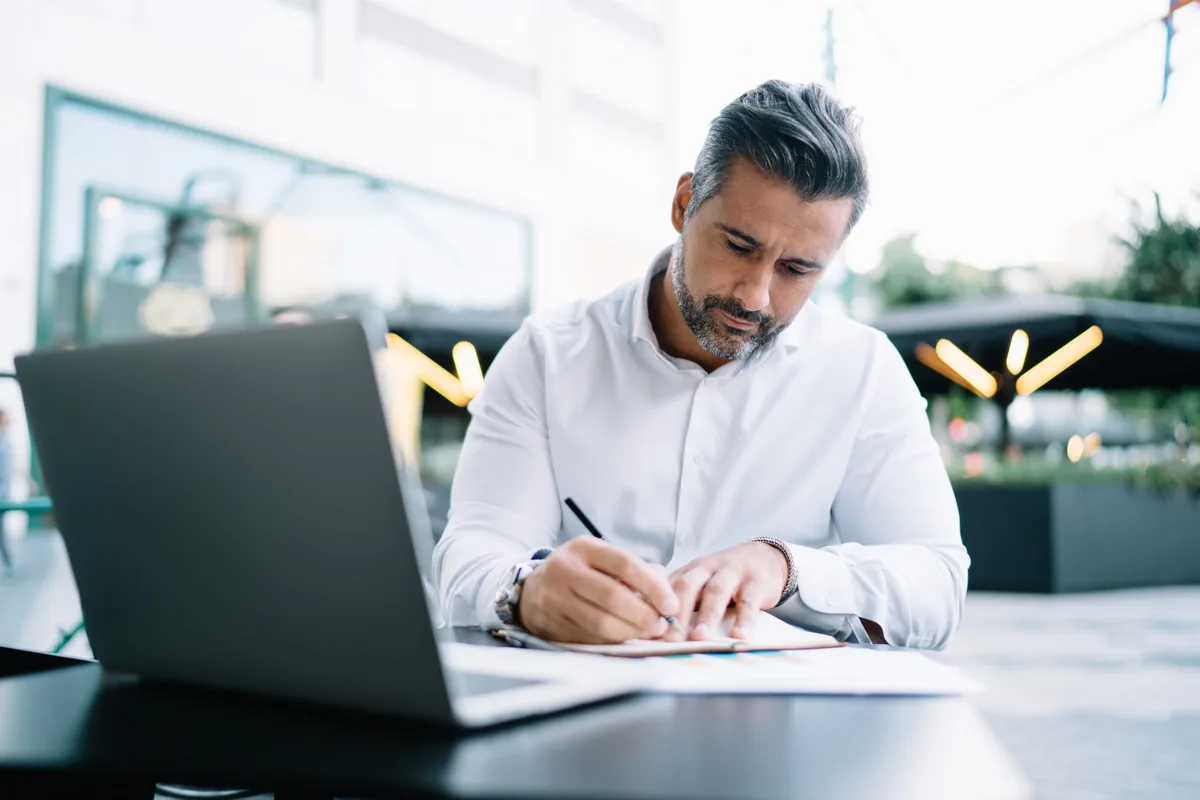 Un entrepreneur prend des notes à la terrasse d'un café